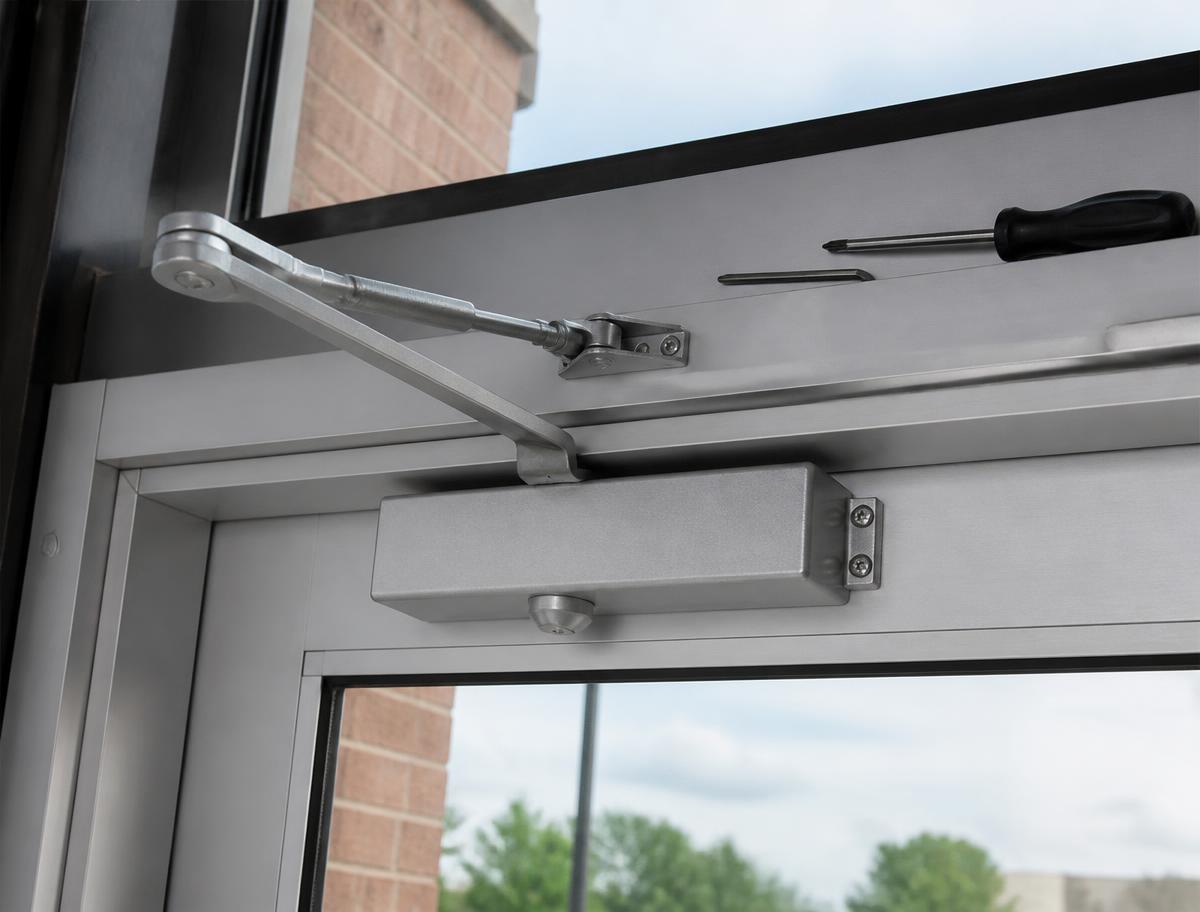 Technician repairing a commercial storefront door and its hardware